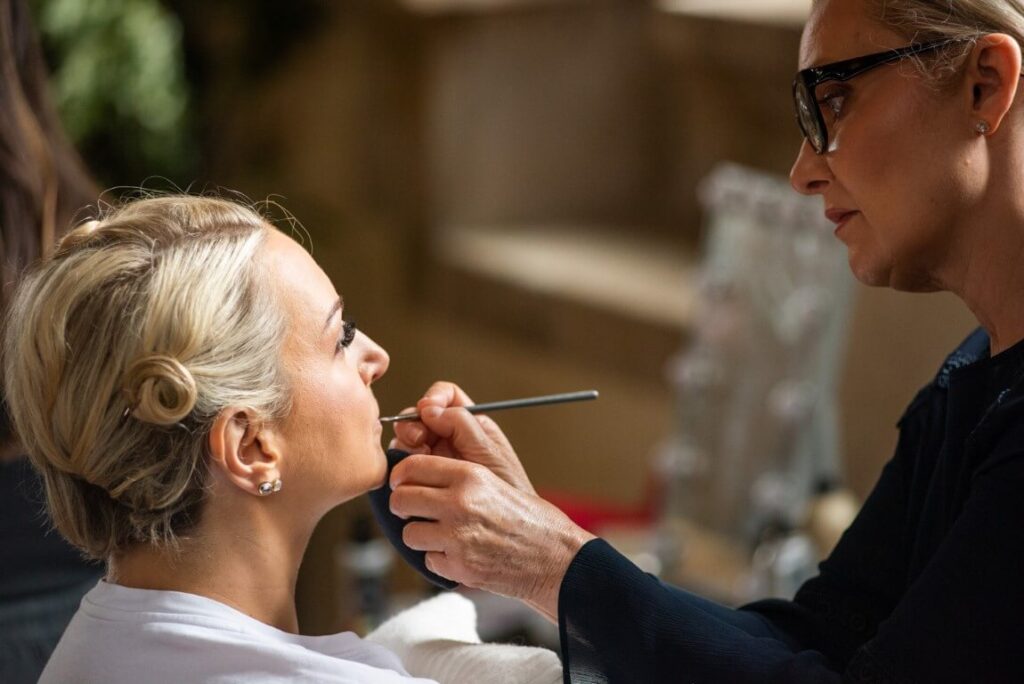A makeup artist applying make up to a bride at Bilsinton Priory in Kent