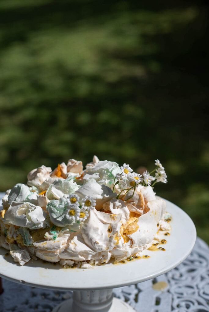A pavlova decorated with daisy's by Blackbird Catering